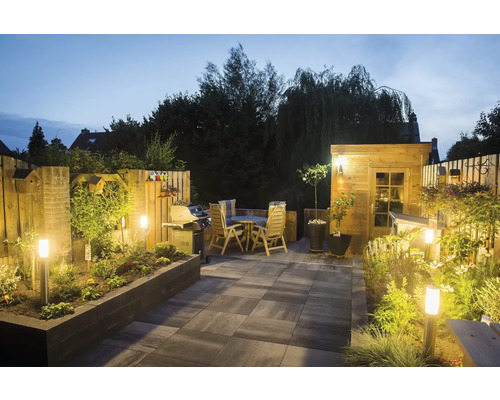 Verlichte tuin met terras, tuinhuis, barbecue en zithoek in de avond.