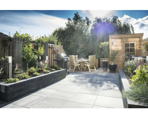 Aangelegde tuin met barbecue, zitgroep, planten en tuinhuis