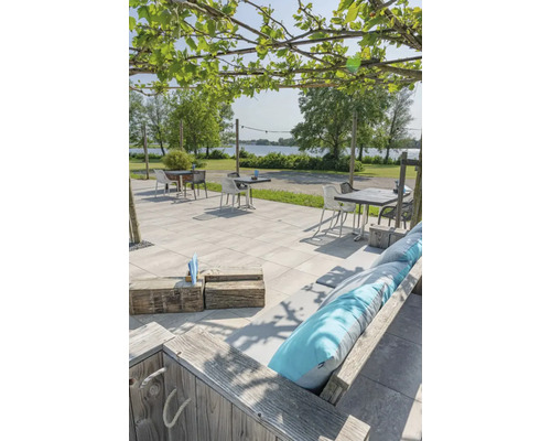 Buitengebied met bestrating, zitplaatsen en uitzicht op een meer