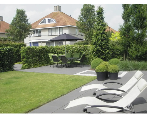 Tuin met gazon, terras met tuinmeubelen, parasol en twee ligstoelen