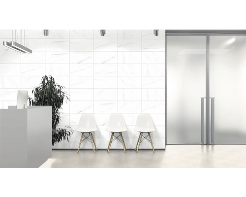 Lichte ruimte met witte wandtegels, receptie, stoelen en plant.