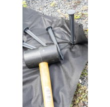 Tuinvlies wordt met een rubberen hamer en grondankers bevestigd.