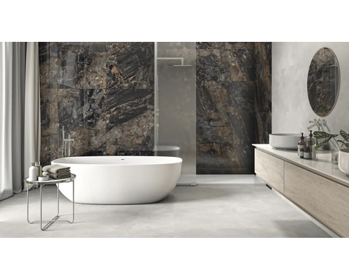 Lichte badkamer met vrijstaand bad, wastafel en donkere wandtegels met marmerlook.