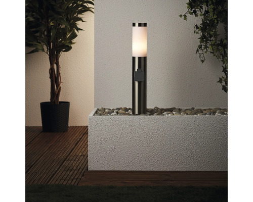 Buitenlamp op stenen in plantenbak naast planten