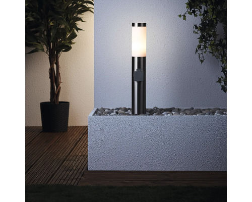 Verlichte sokkellamp in een met stenen gevulde plantenbak naast een plant