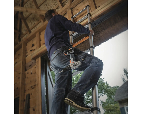 Een persoon beklimt een telescopische ladder en draagt een accuschroevendraaier aan zijn riem.
